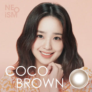 A young woman with wavy dark hair smiles at the camera. The beige background shows “NEO Vision Neoism Coco Brown (50pk)” by NEO Vision, ideal prescription colored contacts for a natural look.