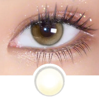 A close-up of a brown eye with long lashes and shimmery shadow, enhanced by EyeCandys Amelie Biscuit Brown circle lens. Below is a yellow-tinted image of the lens, indicating it was used for the look.