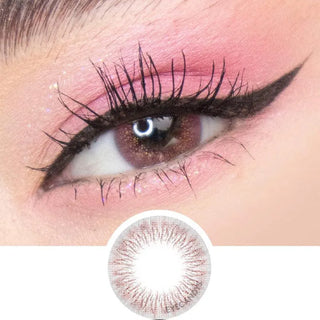 A close-up of an eye with pink eyeshadow, long lashes, black winged liner, and a brown contact lens from the EyeCandys Peach Fuzz Bundle (5 Pairs). Below is a circular detail showing the non-prescription contacts' design.