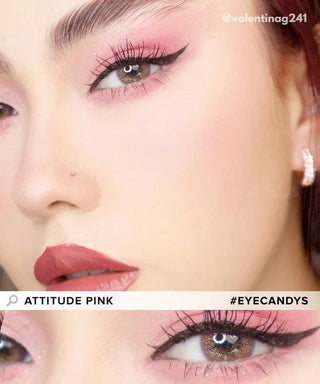 Close-up of a person wearing EyeCandys Attitude Glitter Pink contacts, pink eyeshadow, winged liner, pink lipstick, and soft blush. They sport a nose stud and rhinestone earring. Text reads "ATTITUDE PINK" and "#EYECANDYS".