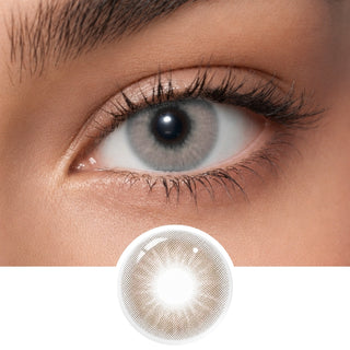 A close-up shows a brown-eyed person wearing EyeCandys Aura Hazel Grey contact lenses with UV blocking. Below the eye, the detailed lens design is displayed. The surrounding skin is smooth with natural makeup.