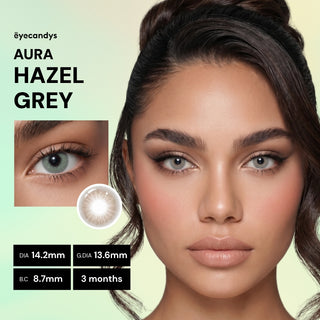 A woman wears EyeCandys Aura Hazel Grey contacts, featuring light hazel-grey tones ideal for brown eyes. An inset close-up shows her eye and the lens design. UV blocking; 14.2mm DIA, 13.6mm G.DIA, 8.7mm B.C., lasts 3 months.