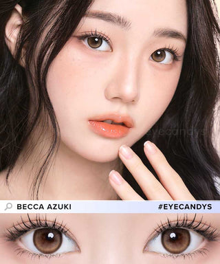 A close-up of a young woman with long dark hair, natural makeup, and glossy peach lips. Her brown eyes are enhanced with i-Girl One Pick Becca Azuki Brown lenses by i-Girl. Text: "Becca Azuki #EYECANDYS.