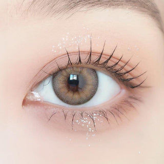 Close-up of model's eye wearing with Ann365 Buttercup Beige Korean color contact lens with prescription, complemented with barely there eye makeup, showing the brightening and enlarging effect of the circle lens on dark brown eyes.