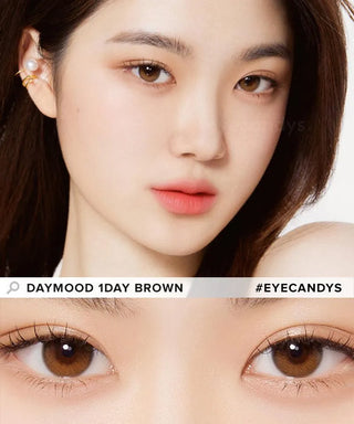 A close-up of a fair-skinned woman wearing Olola Daymood 1-Day Brown contacts. The image highlights her eyes and face. Text reads: "Olola Daymood 1-Day Brown (10pk)" and "#EYECANDYS." Daily disposable, myopia prescription available.