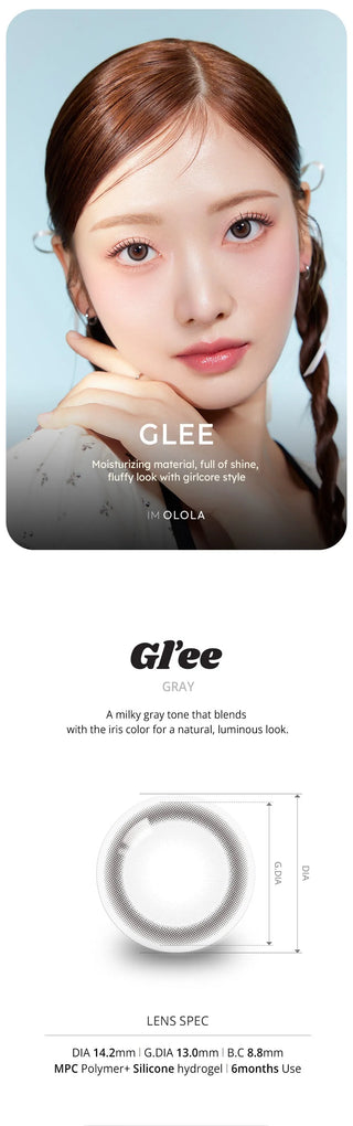 A young woman with flawless skin wears Olola Glee Grey by Olola, posing with her hand near her cheek. Below is a close-up of these non-prescription color contacts, highlighting their natural, luminous grey shade and specs.