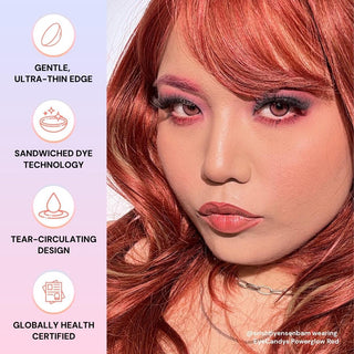 A person with long, wavy red hair and bold pink makeup looks at the camera. Beside them are icons highlighting EyeCandys Powerglow Reddish Pink contact lens features: gentle, ultra-thin edge, sandwiched dye tech, UV protection, and global certification.
