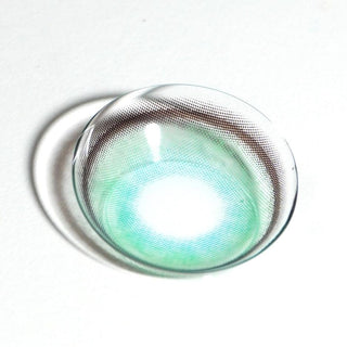 A single EyeCandys Powerglow Turquoise Green contact lens by EyeCandys, showcasing its translucent turquoise green shade and moisture retention, rests on a white surface with a soft shadow.