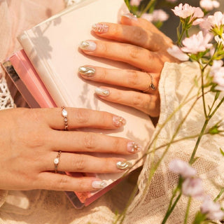 Hand wearing EyeCandys Hanami press on nails featuring pink embossed floral nails, chrome wave accent, and pearl detailing.
