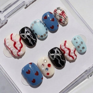 EyeCandys' Heartbreak Hotel Press-On Nails set includes 10 handmade nails with hearts, pearls, polka dots, plaid, white waves, and metallic dots in blue, black, white & red—ideal for a salon-quality gel manicure at home.