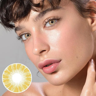 A close-up of a woman with dewy skin and natural makeup. An inset shows EyeCandys Shade Brown contact lenses by EyeCandys, suggesting she is wearing these colored contacts for softly enhanced brown eyes.