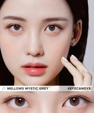 A close-up of a woman with flawless skin wearing Olola Mellows Mystic Grey contact lenses by Olola. She gently touches her cheek, eyes wide open. Below, a zoomed-in image labeled “OLOLA MELLOWS MYSTIC GREY”—available in myopia prescription.