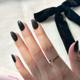 Hand with EyeCandys Meow Me Back Gel nail stickers applied, featuring a sleek black color with glitter accents. Perfect for edgy, glamorous manicures, offering long-lasting wear, easy application, and a sparkling, salon-quality gel finish for eye-catching nails.