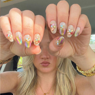 Hand wearing reusable Miraflores press on nails featuring multicolor cat eye nails, floral gold detailing, and 3D opal flower accent.