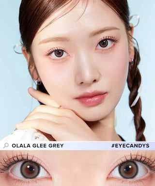 A woman with braided hair wears Olola Glee Grey by Olola, shown in a close-up of her eyes. She has natural makeup with light blush and pink lips. The text reads "OLALA GLEE GREY #EYECANDYS.