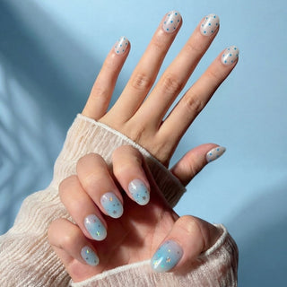 Close up hand showcasing EyeCandys Plot Twist press on nails with split design, holographic star confetti, and blue polka dot nail art.