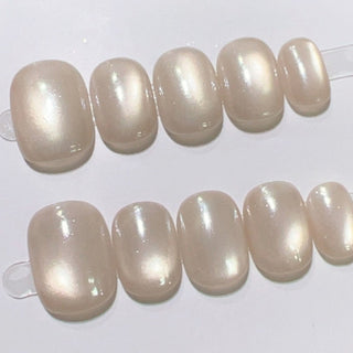 Close-up of EyeCandys Moon Syrup press on nails on a white background featuring semi-sheer jelly nude base with pearly cat-eye glow and glossy natural finish.