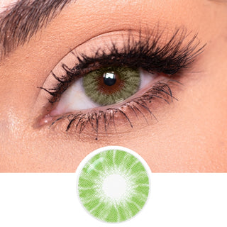 A close-up of a green eye with dramatic pink and gold eyeshadow, long lashes, and light blonde hair. Below is EyeCandys Shade Green contact lens by EyeCandys—natural green with a patterned design, ideal for dark eyes.