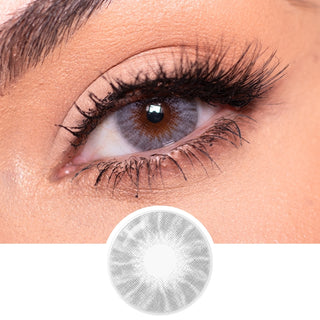 A close-up of an eye with dramatic red and gold makeup, long lashes, and EyeCandys Shade Grey contact lens by EyeCandys. Curly light pink hair frames the eye, showing off the striking effect of these grey contacts for dark eyes.
