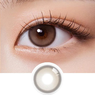 A close-up of a brown eye with long lashes wearing Olola Purity Shine 1-Day Taupe Brown color contact lens. Below, an Olola daily disposable lens from the 10-pack is shown on a white background.