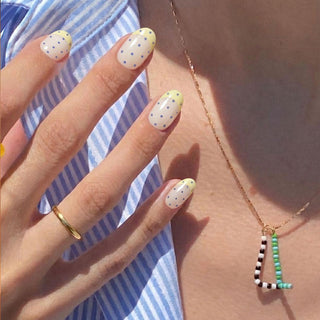 Hand wearing Sunday Dots reusable press on nails with cute pastel French tips and scattered periwinkle dots for a light, playful manicure.