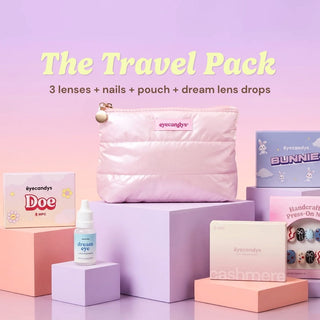 A pink pouch with an “EyeCandys” label, color contact lens boxes, Dream Lens Drops, and a press-on nail set are arranged on pastel blocks. Text above reads: “The Complete Travel Pack by EyeCandys: 3 lenses + nails + pouch + lubricating eye drops.”.