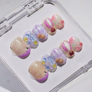 EyeCandys Up Up & Away Press-On Nails feature handmade plaid patterns, pastel gradients, and 3D accents like pearls, gems, and hearts in a clear case for a salon gel manicure look.
