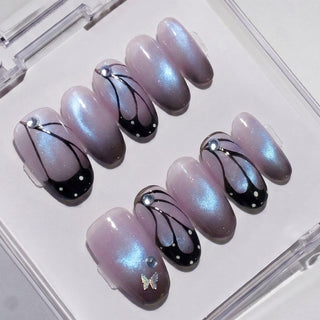 EyeCandys Wing Woman Press-On Nails feature glossy lavender nails with a shimmery finish, black and white butterfly wing designs, dots, rhinestones, plus metallic bow and gem accents for a salon-style gel manicure.