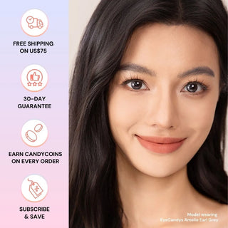 A woman with long dark hair smiles, wearing EyeCandys Amelie Earl Grey lenses for a natural look. Icons show benefits: free shipping over $75, 30-day guarantee, Candycoins on orders, and subscribe & save.