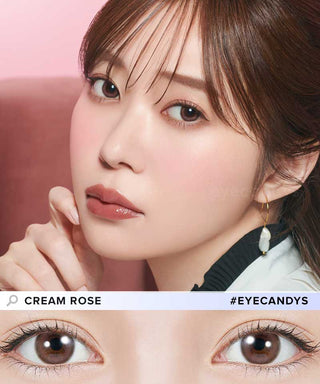 A woman with straight brown hair and soft pink makeup poses with her hand near her face, showcasing her brown eyes enhanced by Topards 1-Day Cream Rose (10pk) contact lenses with UV protection from Topards.
