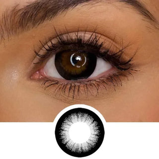 A close-up of a brown eye with long lashes wearing EyeCandys Extra Magic Black lenses by EyeCandys; below is a graphic highlighting the lens’s soft dark outer ring and lighter center for an enlarging effect.