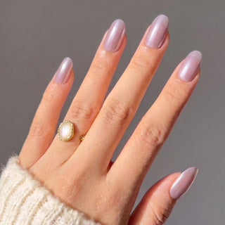 Hand wearing Eyecandys Taro Latte press-on nails with a glossy taro purple chrome finish, glazed effect, and salon-quality short oval shape.