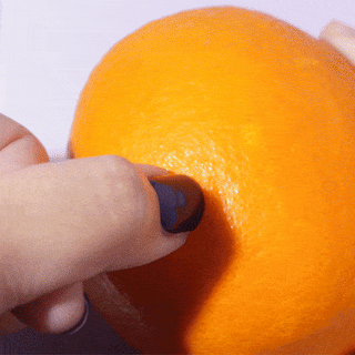 Peeling orange with a hand featuring EyeCandys Gel Nail Stickers, showcasing vibrant nail art and a glossy gel-like finish for a long-lasting manicure