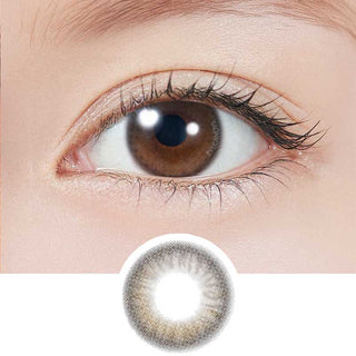 A close-up of a brown eye with long lashes. Below is a Topards 1-Day Glow Brown (10pk) daily contact lens by Topards, shown on a white background, featuring UV protection.