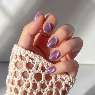 Hand wearing EyeCandys Grape Jelly press on nails featuring mauve purple jelly nails with iridescent pink and gold shimmer.