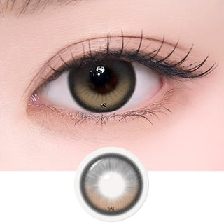 Close-up of an eye with long lashes wearing i-SHA Reborn Red 1-Day Creamy Brown (10pk) colored contact lenses, featuring a warm chocolate brown ribbon-lace design with subtle red undertones for soft, natural depth. Silicone hydrogel daily lenses with fixed-axis weighted technology for comfortable everyday wear.
