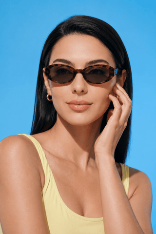 Model wearing EyeCandys Jellicle Oval tortoiseshell full-frame sunglasses. Lightweight TR oval frames with a minimalist 90s-inspired unisex design, flattering diamond and heart face shapes.