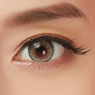 A close-up of a brown eye with long lashes and a defined brow, enhanced by NEO Vision Glamour Grey (Custom Toric for Astigmatism) contacts, highlighting natural makeup and subtle elegance.