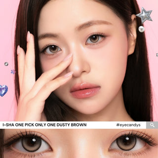 A woman with long dark hair poses, showing her i-Sha One Pick Only One 1-Day Dusty Brown (10pk) contact lenses by i-Sha. Decorative stars and hearts float around her on a pink background, highlighting the natural eye enhancement these daily disposable colored contacts provide. A close-up of her eyes is shown at the bottom.