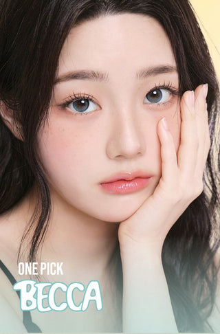 A young woman with long dark hair and light blue eyes, wearing i-Girl One Pick Becca Matcha Blue contacts by i-Girl, gazes softly at the camera with her face resting on her hand. Text below reads "ONE PICK BECCA.