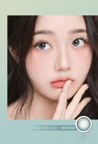 A woman with fair skin and long dark hair gazes upward, her finger near her lips, wearing i-Girl One Pick Becca Matcha Blue contacts for a natural look. Text reads "i-Girl One Pick Becca Matcha Blue" beside an image of a contact lens.