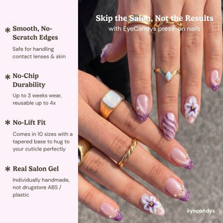 A close-up of hands with long, almond-shaped Aloha Darling Press-On Nails by EyeCandys, featuring a pink base, purple French tips, and white floral designs. Enjoy salon gel manicure quality and easy application at home.