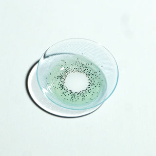 A close-up of the EyeCandys Pink Label Amalfi Blue contact lens, featuring a dotted pattern, is shown on a white surface, highlighting its vibrant blue color and unique design.