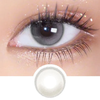 A close-up of an eye with long lashes and shimmery gold eyeshadow wears EyeCandys Amelie Earl Grey circle lenses for a natural look. Below is a circular image showing the design from EyeCandys.