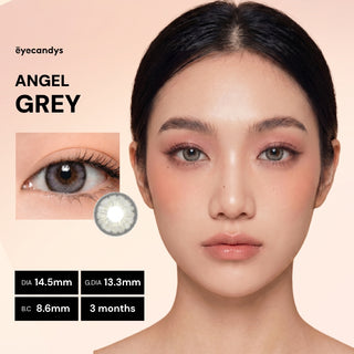 A woman with smooth skin wears EyeCandys Pink Label Angel Grey color contacts. An inset shows a close-up of her eye with the lenses. Text lists: "PINK LABEL ANGEL GREY," DIA 14.5mm, G.DIA 13.3mm, B.C 8.6mm, 3 months, EyeCandys logo.