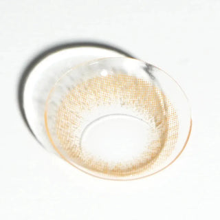 A close-up of the EyeCandys Attitude Glitter Brown contact lens by EyeCandys, featuring a visible light brown pattern on a white surface—showcasing stylish and comfortable colored contacts.