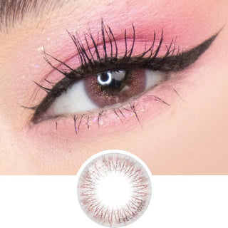 A close-up of an eye with long lashes, black winged eyeliner, pink eyeshadow, and sparkly makeup. Below is EyeCandys Attitude Glitter Pink colored contacts by EyeCandys, featuring a detailed pattern for a seamless look.
