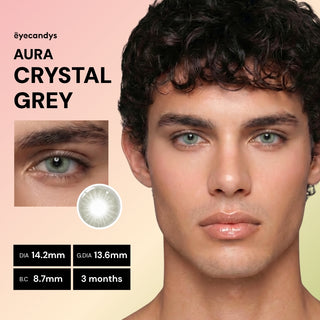 A close-up of a male wearing EyeCandys Aura Crystal Grey contacts, with an inset of her eye and details: diameter 14.2mm, graphic diameter 13.6mm, base curve 8.7mm, lasts 3 months.