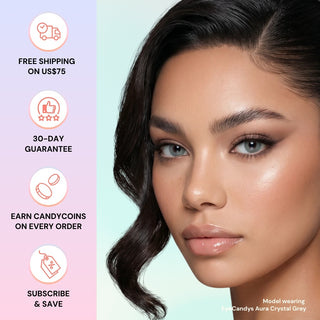 A woman with glowing makeup and wavy dark hair wears EyeCandys Aura Crystal Grey contacts. Beside her: icons and text—free shipping on US$75, 30-day guarantee, earn Candycoins, and subscribe & save.