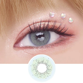 A close-up of an eye wearing EyeCandys Pink Label Amalfi Blue contacts, with long lashes, shimmery pink eyeshadow, and three iridescent rhinestones above the eyelid. Below is the Pink Label Amalfi Blue lens design.